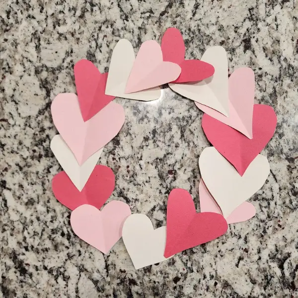 using cut out hearts in red, white, and pink construction paper to make a wreath for a simple valentine's day activity