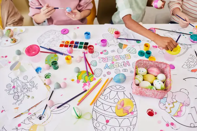 Children sit at a table crafting easter themed coloring sheets.
